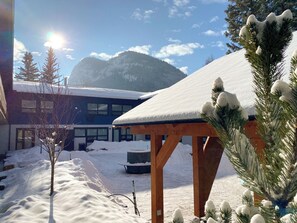 A snow-covered outdoor area with a wooden pergola, a building with large windows, and a mountain in the background. - The Dorothy Motel (Banff)
