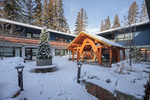 A snow-covered outdoor area with a wooden gazebo, benches, and a snow-covered Christmas tree. - The Dorothy Motel (Banff)