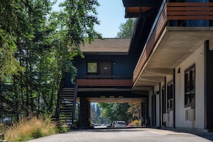 A two-story building with a stone foundation, a wooden deck, and a covered walkway.