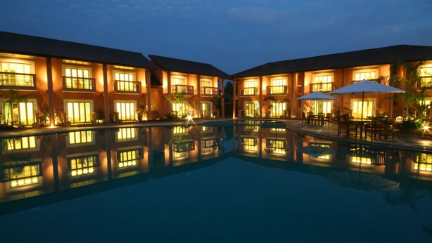 Un hotel con piscina, diversi balconi e zone relax all'aperto.