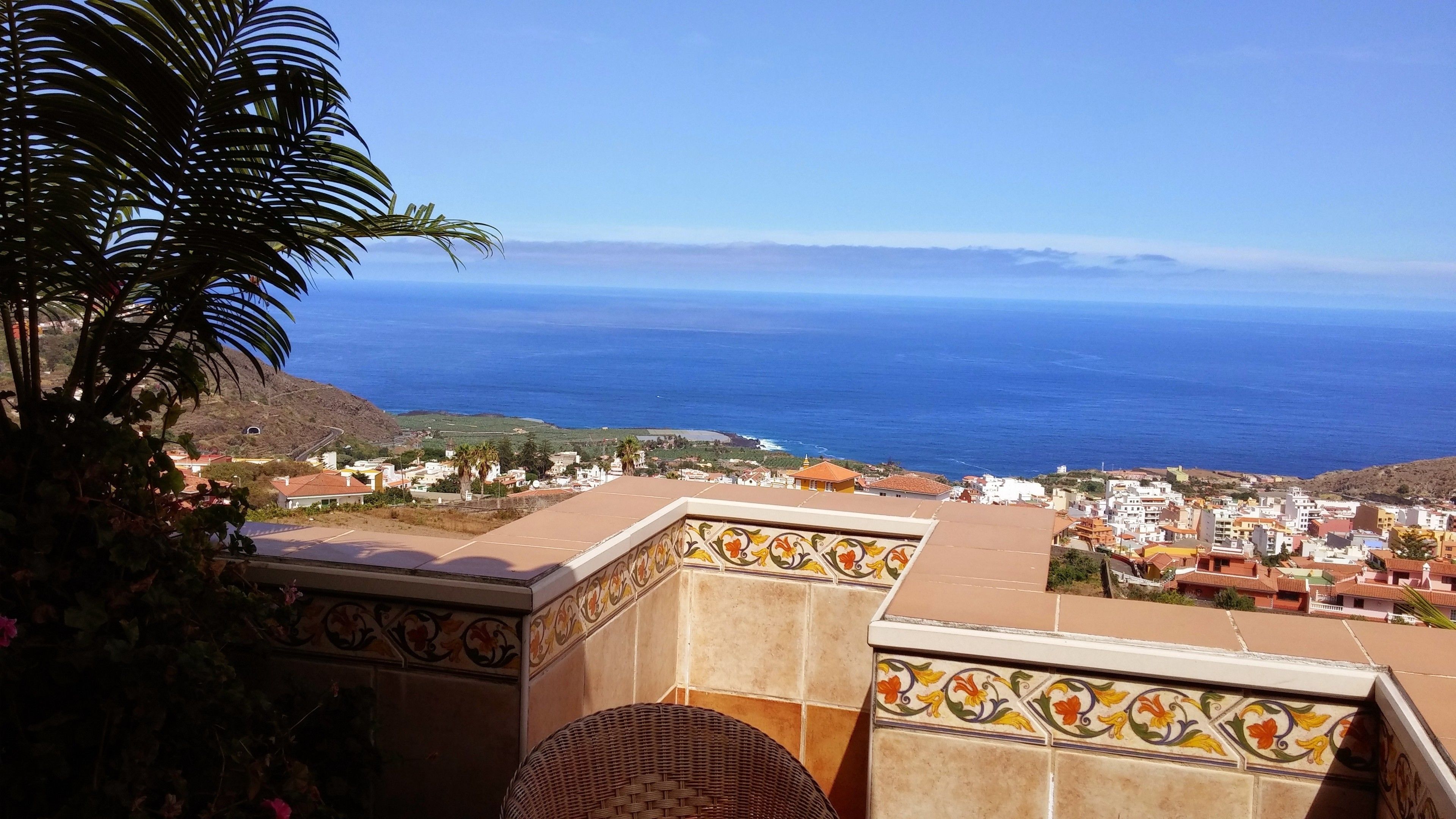 A terrace with a view of the ocean and a coastal town.