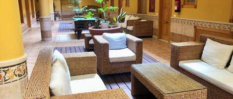 A covered outdoor seating area with wicker furniture and potted plants.