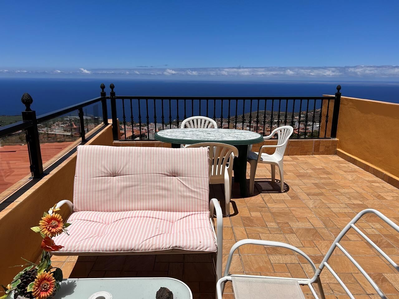 Uma varanda com vista para o oceano, uma mesa e duas cadeiras.