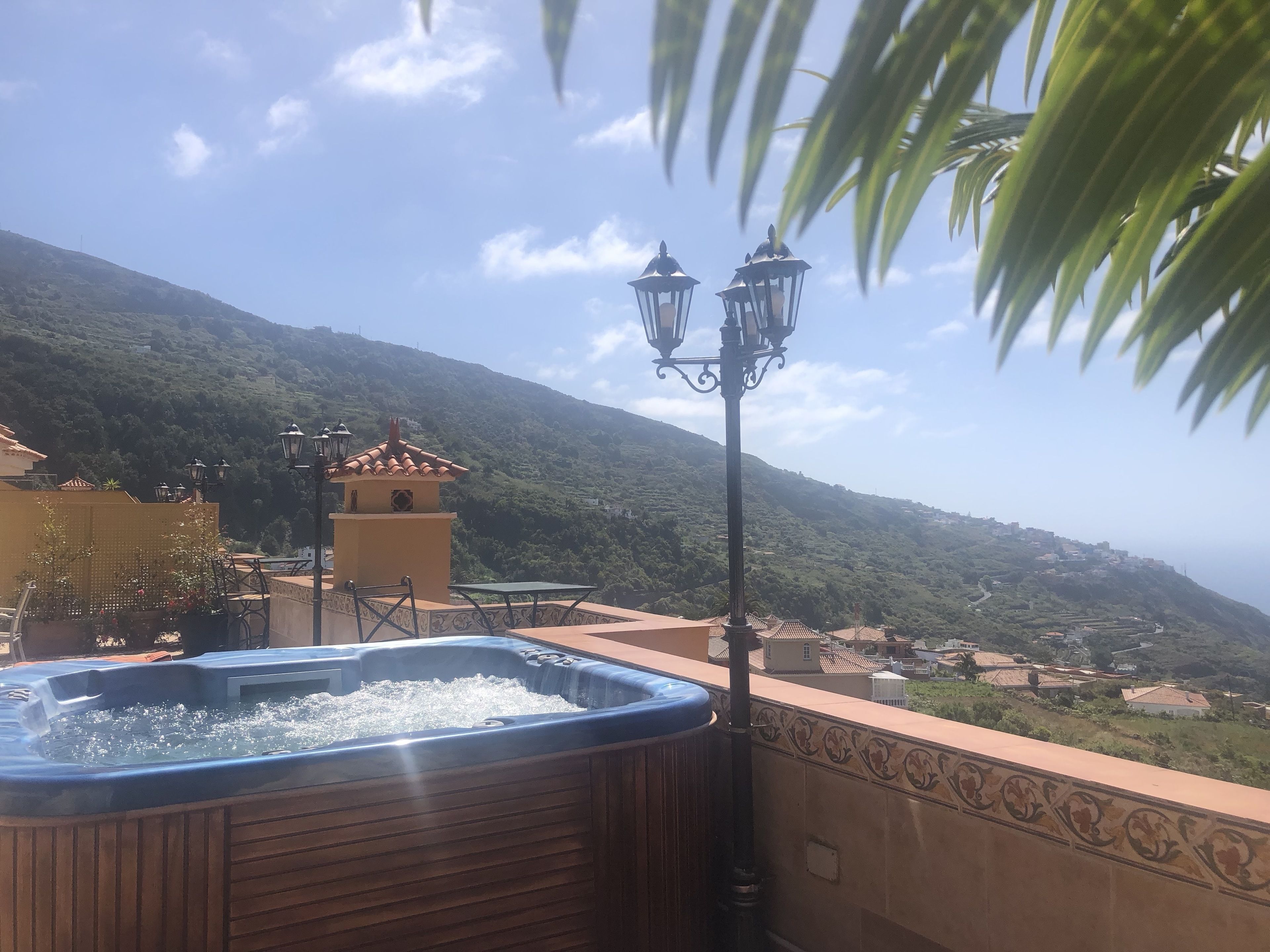 A hot tub on a balcony with a view of a hillside town.