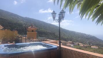 Un jacuzzi en un balcón con vistas a un pueblo en la ladera.