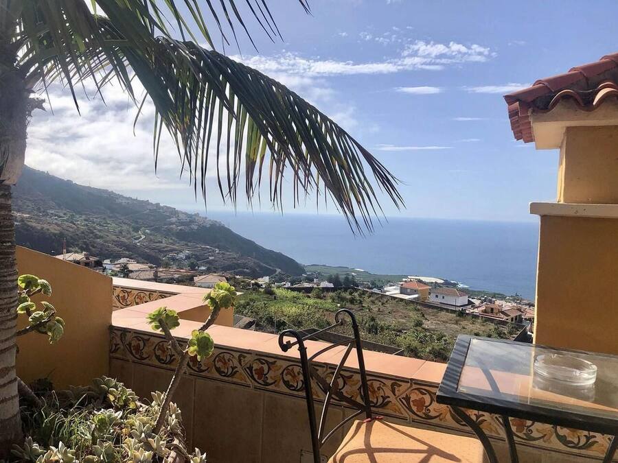 Ein Balkon mit Blick auf das Meer und eine Stadt in der Ferne.