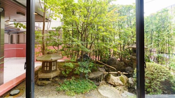 Un jardin japonais traditionnel agrémenté d’une lanterne en pierre, de rochers et d’arbres.