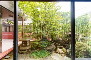 A traditional Japanese garden with a stone lantern, rocks, and trees. - Kyoto Horikawa Inn (Kyoto)
