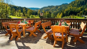 A terrace with wooden furniture and a view of a forested valley. - AlpenParks Hagan Lodge Altaussee (Altaussee)