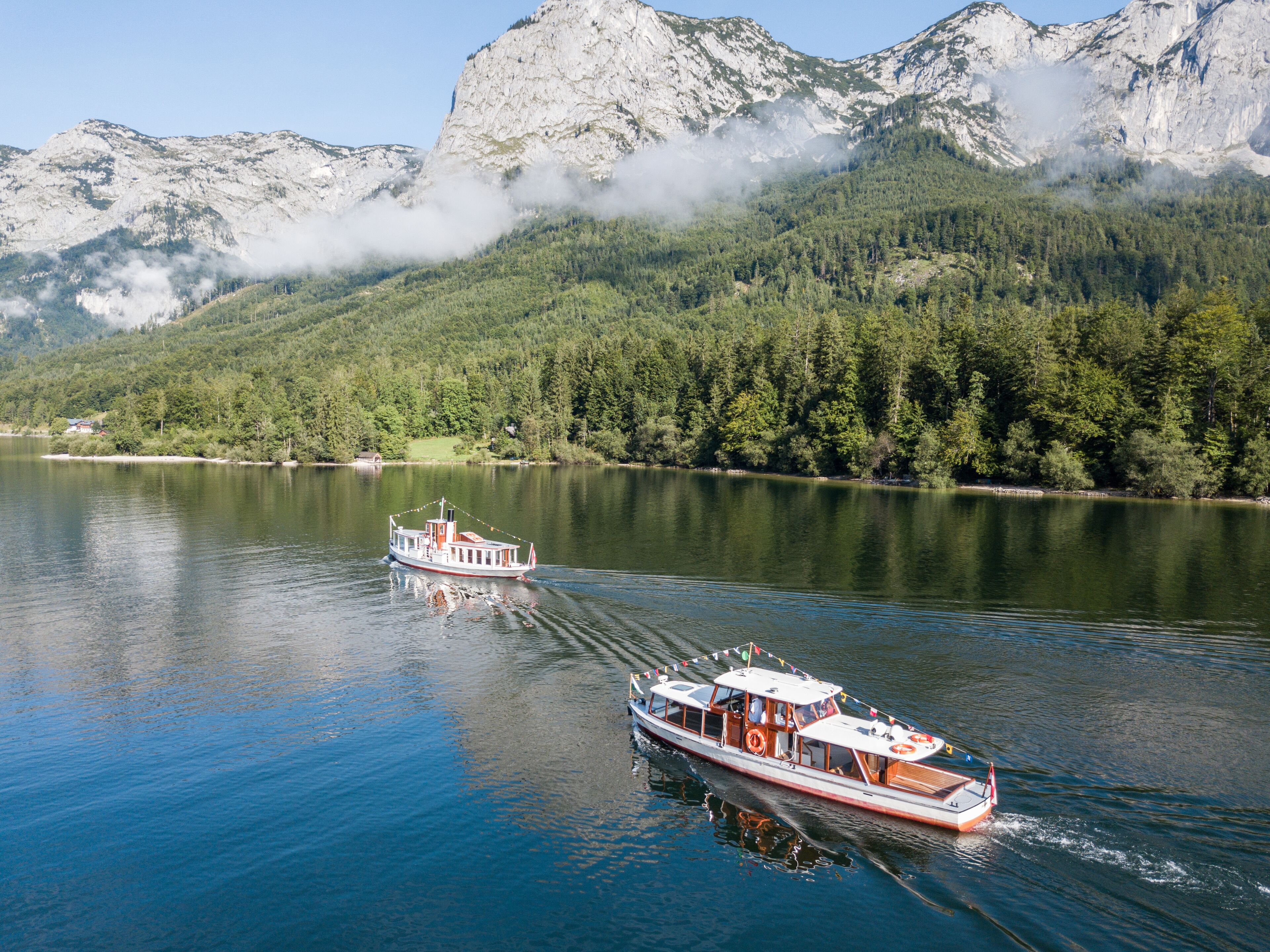 A boat on a calm lake with a mountainous backdrop.