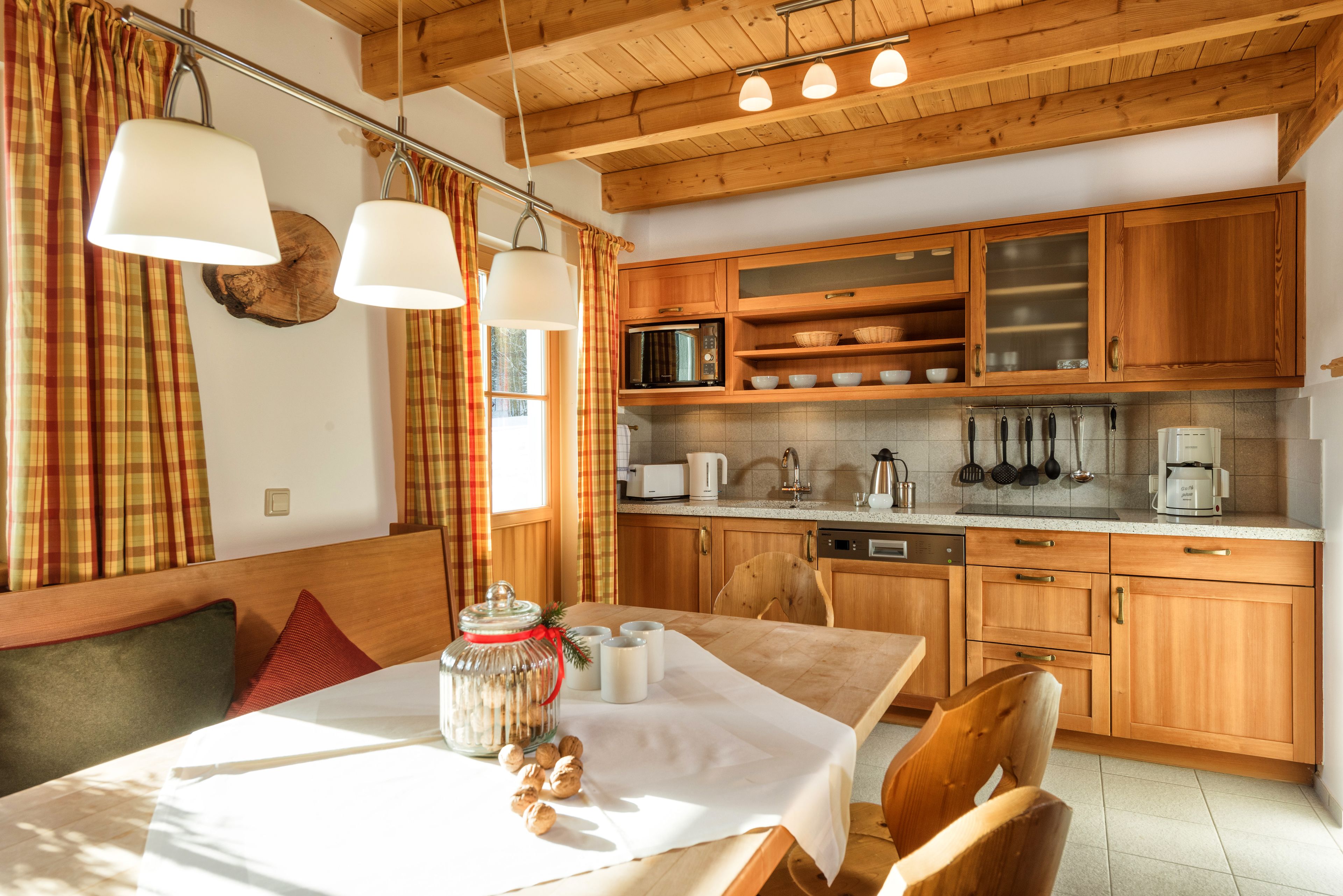 A cozy kitchen with wooden cabinets, a dining table with a white tablecloth, and a breakfast setup.