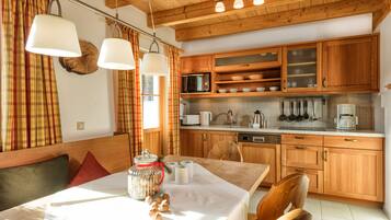 A cozy kitchen with wooden cabinets, a dining table with a white tablecloth, and a breakfast setup.