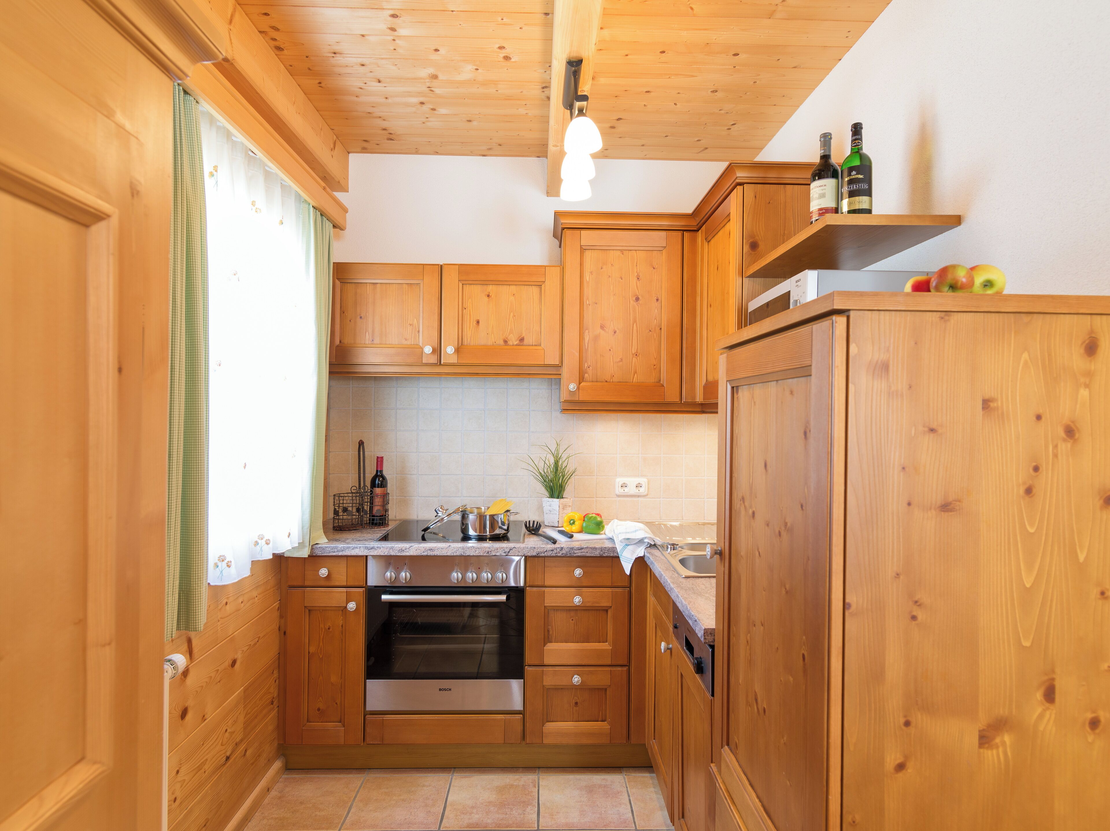 A kitchen with wooden cabinets, a Bosch oven, and a countertop with various items.