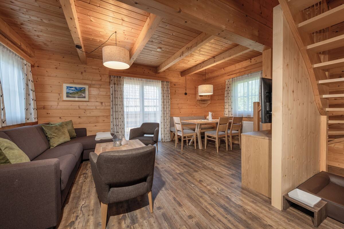 Un intérieur en bois comprenant un canapé, des fauteuils, une table à manger et un escalier.
