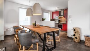 Una cocina moderna con gabinetes rojos, una mesa de comedor de madera y sillas grises.