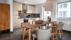 Una cocina moderna con baldosas oscuras, una mesa de comedor de madera y sillas grises.