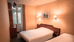 A hotel room with two beds, a desk, a chair, a window with curtains, and two wall-mounted lamps. - Hotel Neptune (Paris)