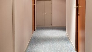 A hallway with a patterned carpet, beige walls, and wooden doors. - Hotel Neptune (Paris)