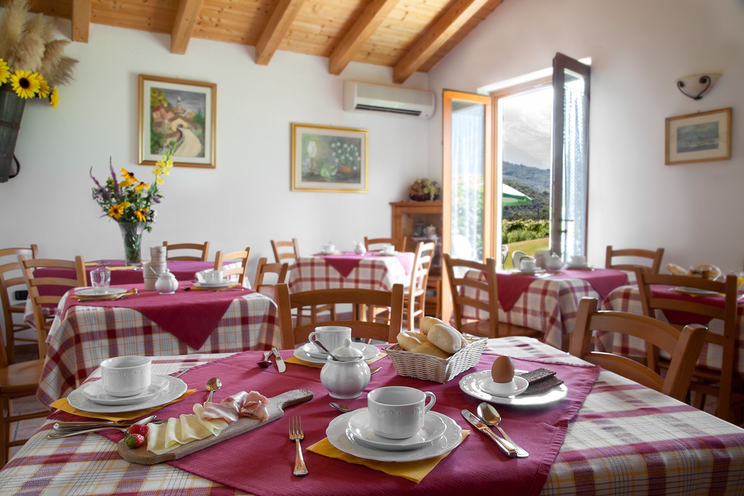A dining area with tables set for breakfast, featuring bread, eggs, and pastries.