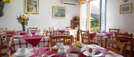 A dining area with tables set for breakfast, featuring bread, eggs, and pastries.