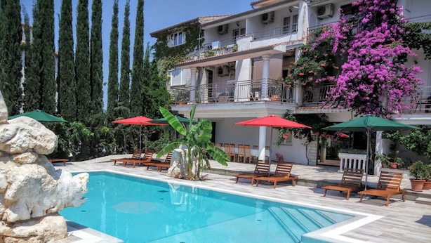A pool area with lounge chairs and umbrellas, a hot tub, and a stone wall. - Gargamelo Pension (Porec)