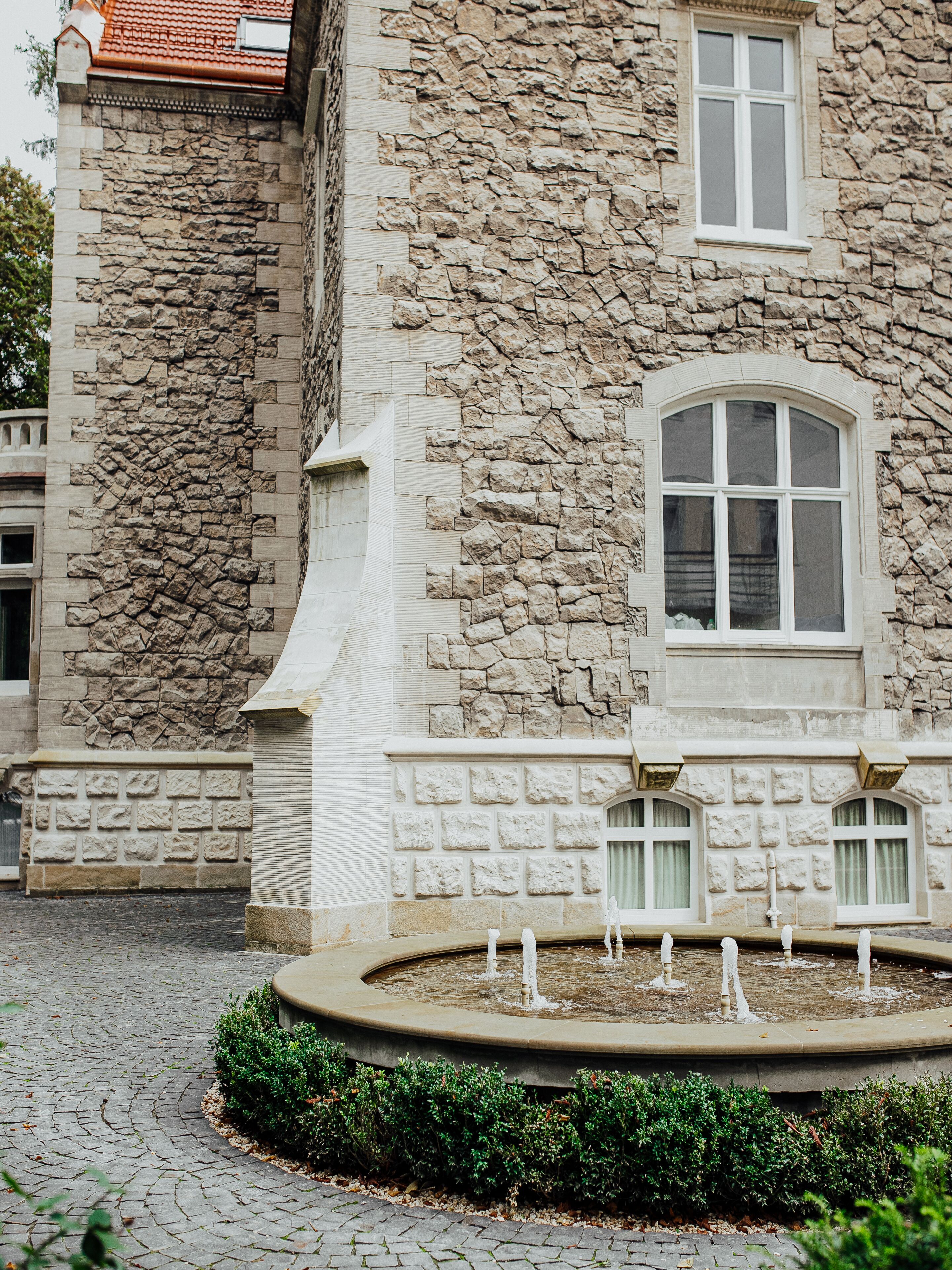 A stone building with a fountain in front.