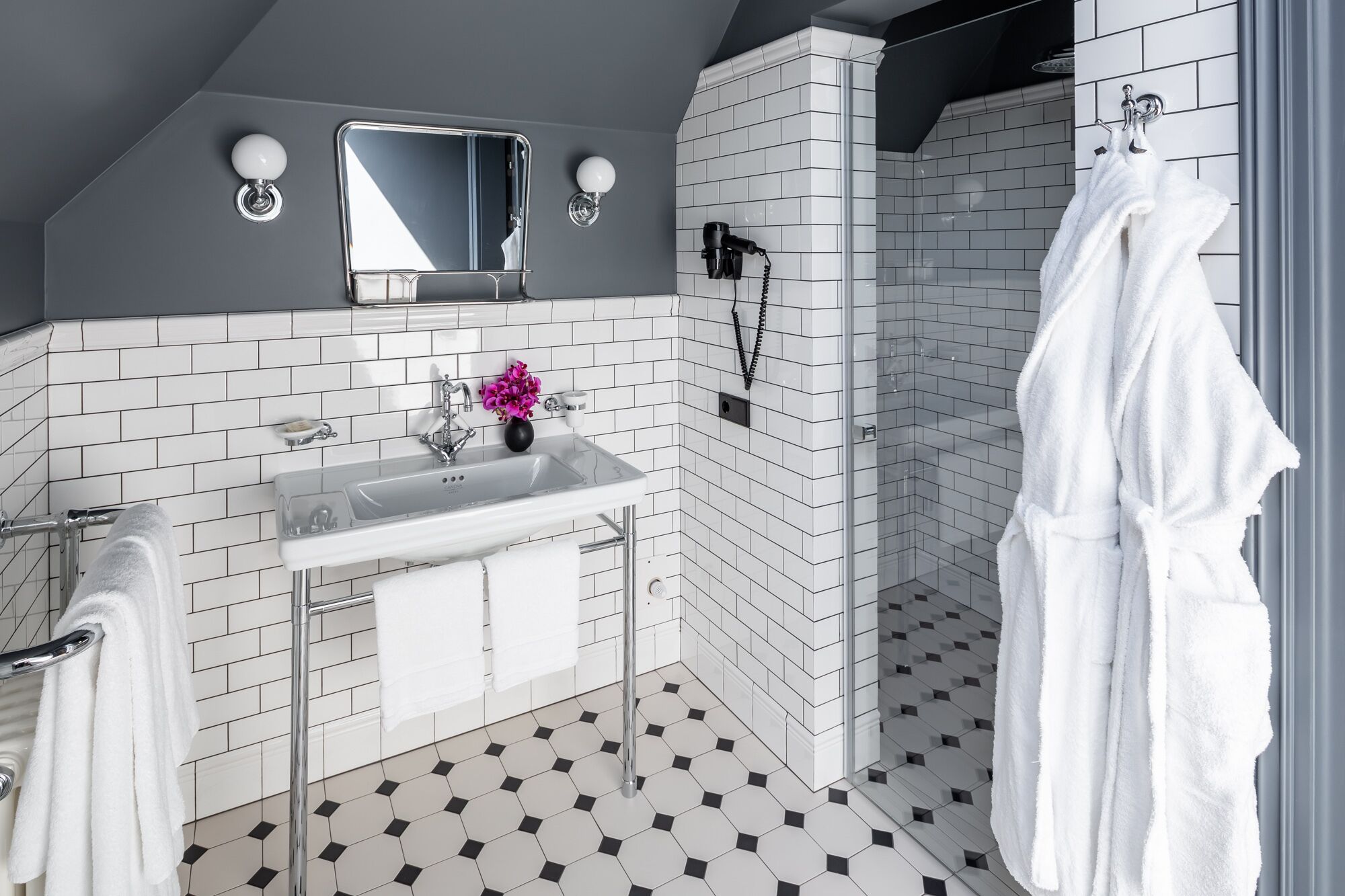 Een moderne badkamer met een wit wastafelmeubel, spiegel en een zwart-wit betegelde vloer.