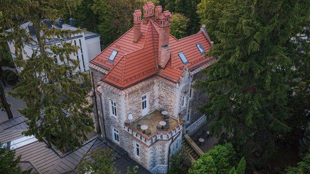A stone building with a red roof, surrounded by trees. - Lion's Castle (Lviv)