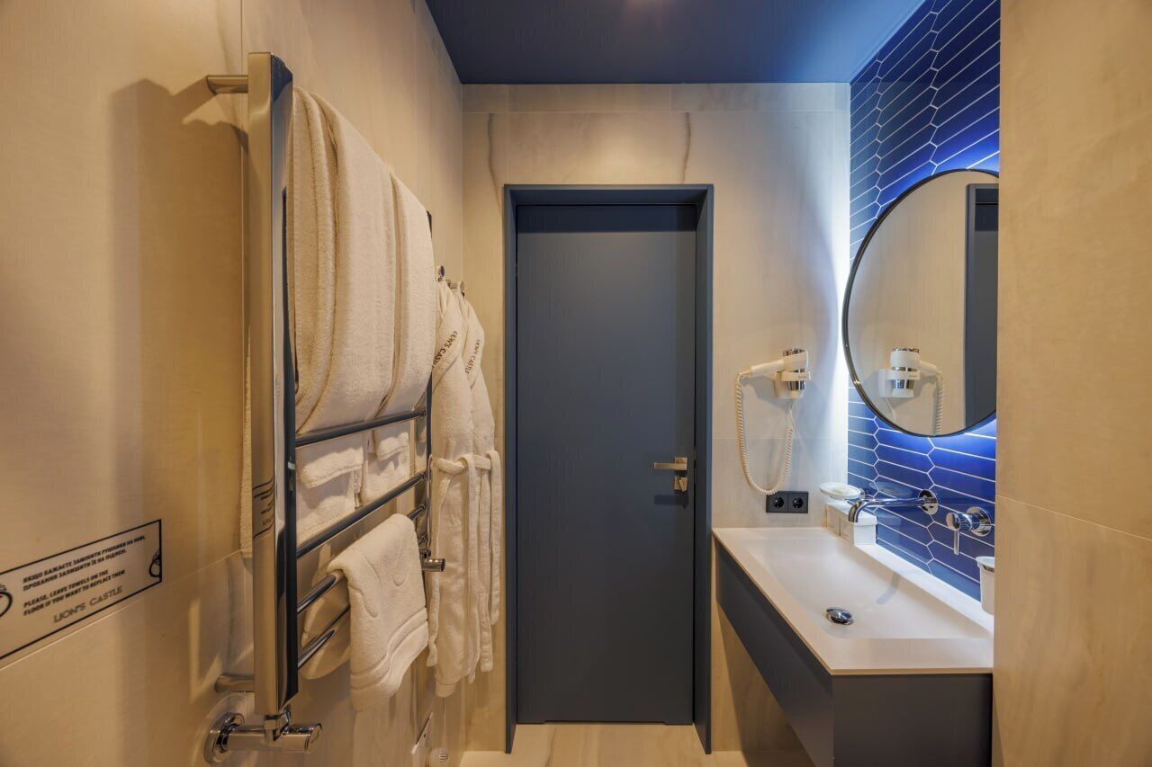 Un baño moderno con toallero, una puerta y un lavabo con espejo.