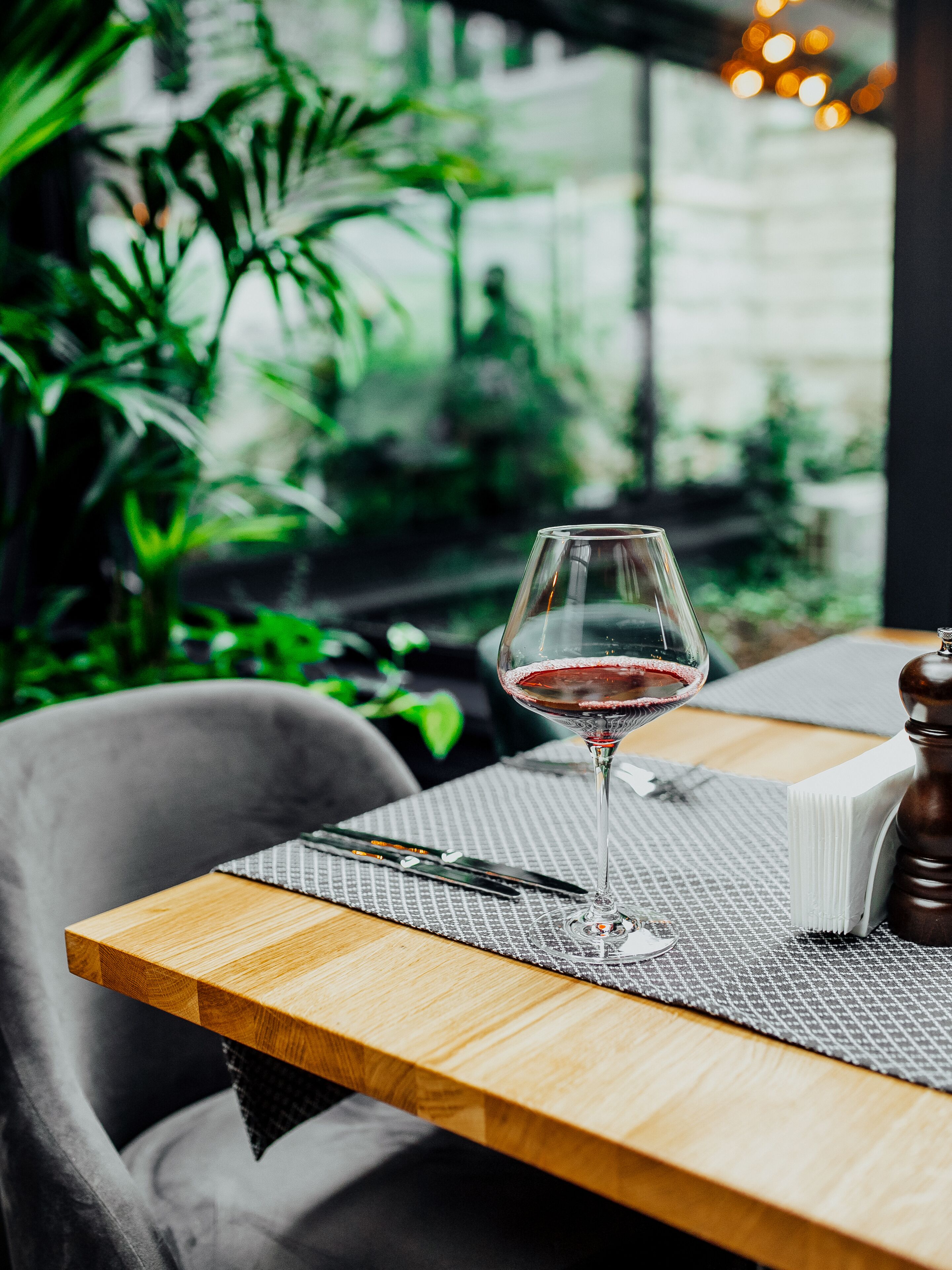 Uma mesa com um copo de vinho tinto, um livro e um saleiro.