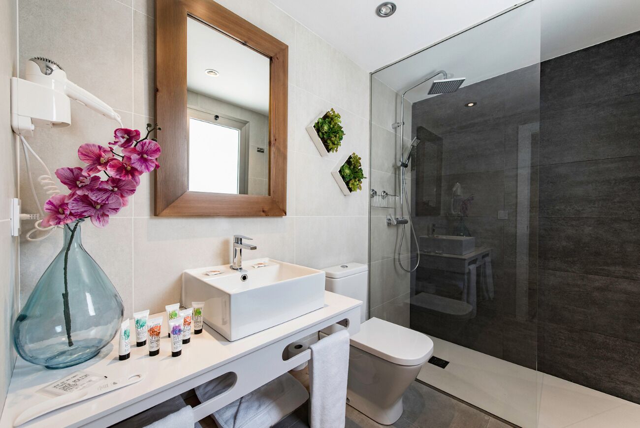 Een moderne badkamer met een wit wastafelmeubel, spiegel en een douchecabine van glas.