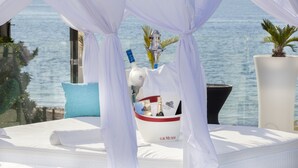 A bed with a white canopy, a bottle of champagne, and a tray with a bottle of water and a glass. - Marina Playa Hotel Apartments by Typic Hotels – Adults Only (Sant Antoni de Portmany)