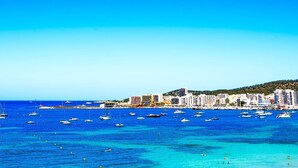 A coastal cityscape with numerous boats on the water and a hilly backdrop. - Marina Playa Hotel Apartments by Typic Hotels – Adults Only (Sant Antoni de Portmany)