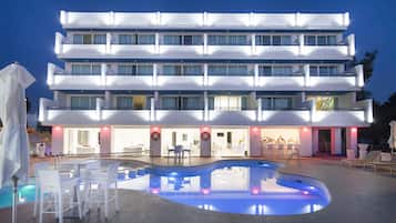 A multi-story hotel with a swimming pool and outdoor seating area.