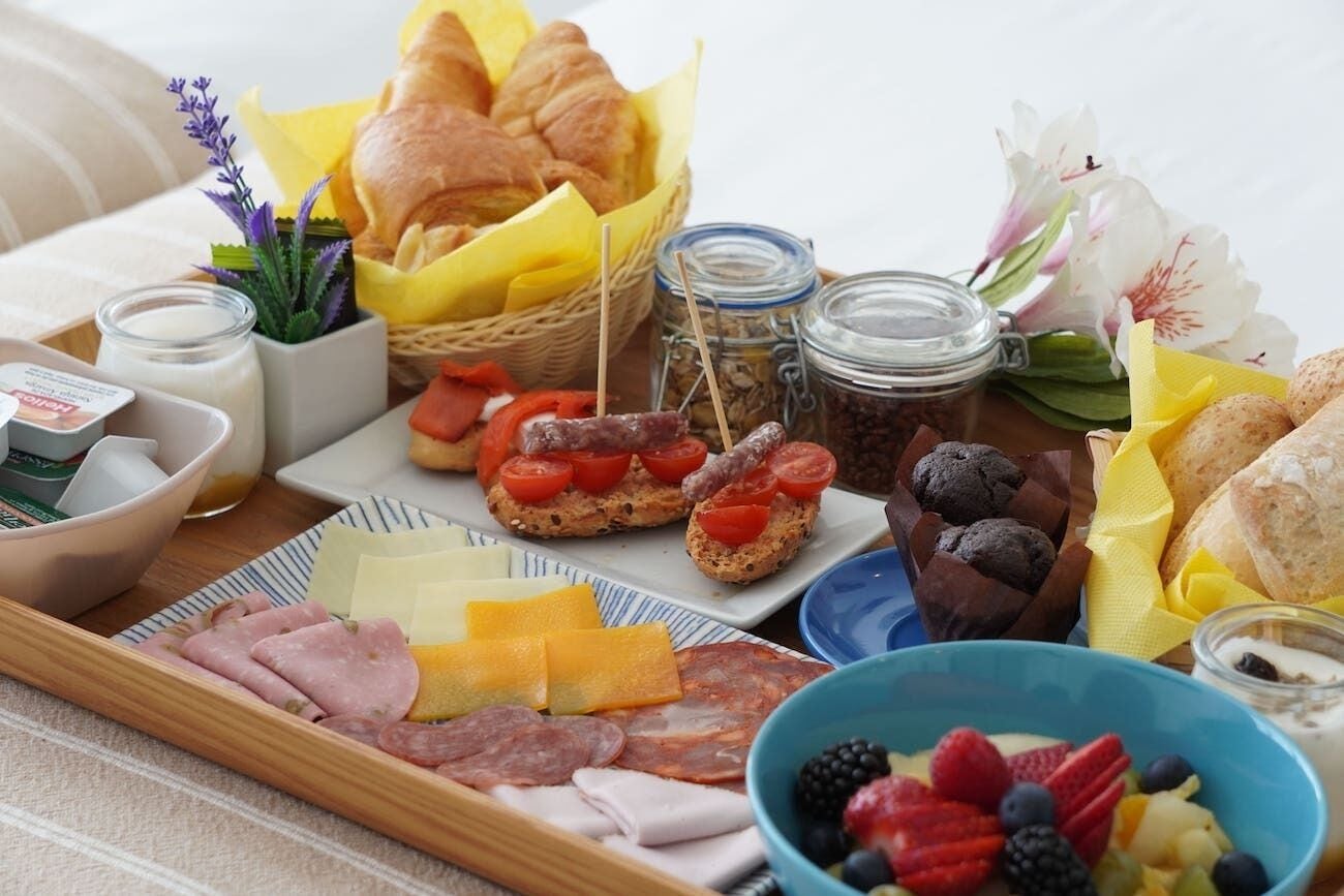 Ein Frühstückswagen mit verschiedenen Speisen, darunter Brot, Käse, Fleisch und Obst.
