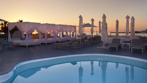 A poolside area with lounge chairs and umbrellas, a clear pool, and a sunset view. - Marina Playa Hotel Apartments by Typic Hotels – Adults Only (Sant Antoni de Portmany)