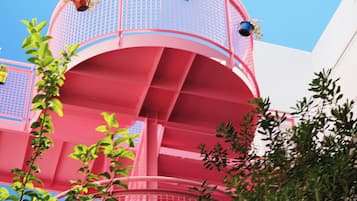 Una struttura architettonica rosa con balconi e piante.