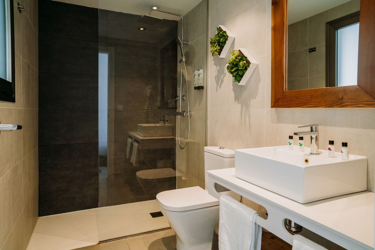 Ein modernes Badezimmer mit einer gläsernen Duschkabine, einem weißen Waschbecken und einer Toilette.