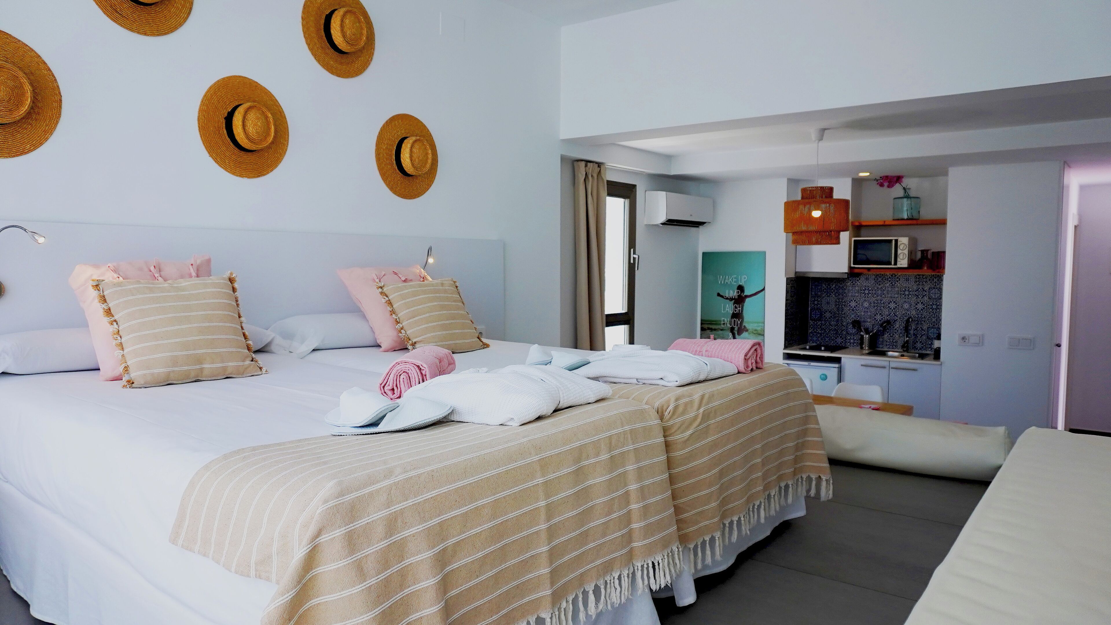 A hotel room with a large bed, a small kitchenette, and a bathroom visible through an open door.