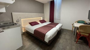 Una habitación de hotel con cama, escritorio, silla y kitchenette.
