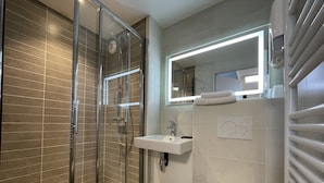 Un baño moderno con ducha de vidrio, lavamanos y retrete.