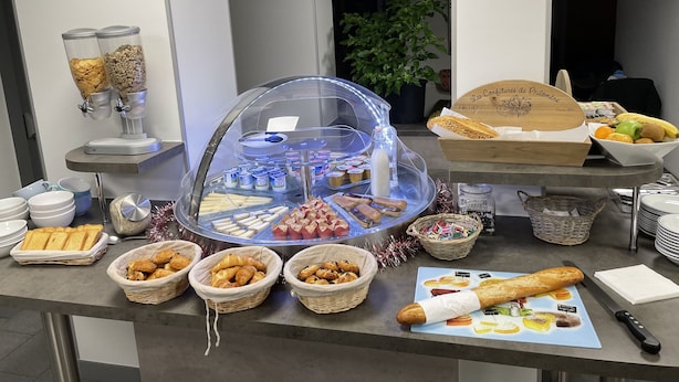Montaje de bufé con diferentes opciones de comida, incluyendo pasteles, pan y una selección de bebidas.