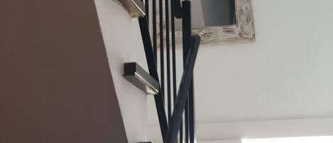 Una escalera con barandilla negra y un espejo decorativo en la pared.