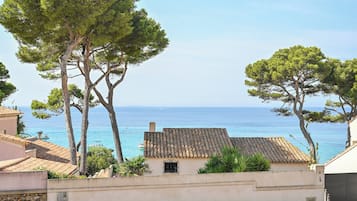 Un bâtiment situé sur la côte, doté d’un toit en tuiles, entouré d’arbres et offrant une vue sur la mer.