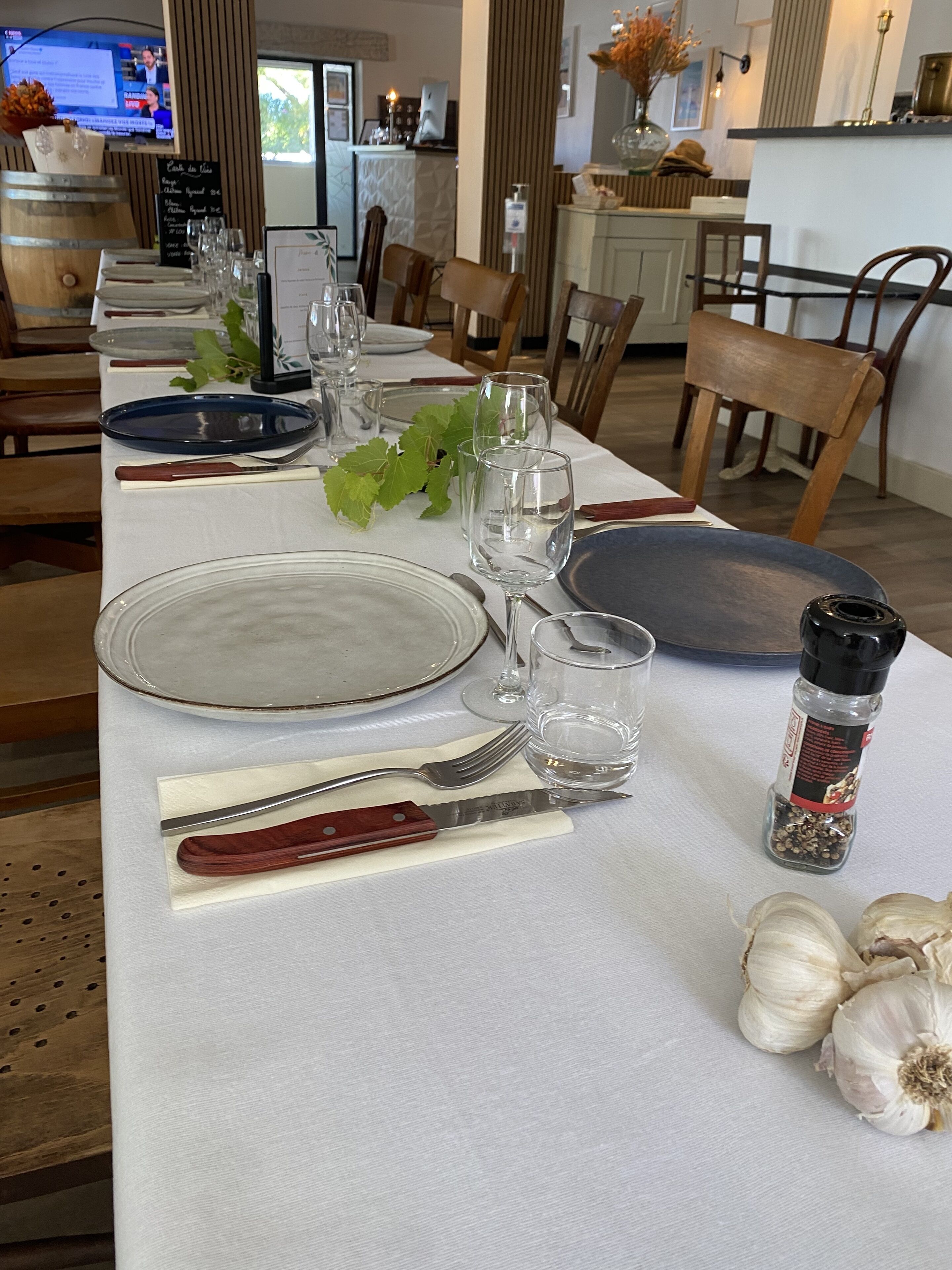 Een eettafel gedekt met borden, bestek, glazen en een peperbus.