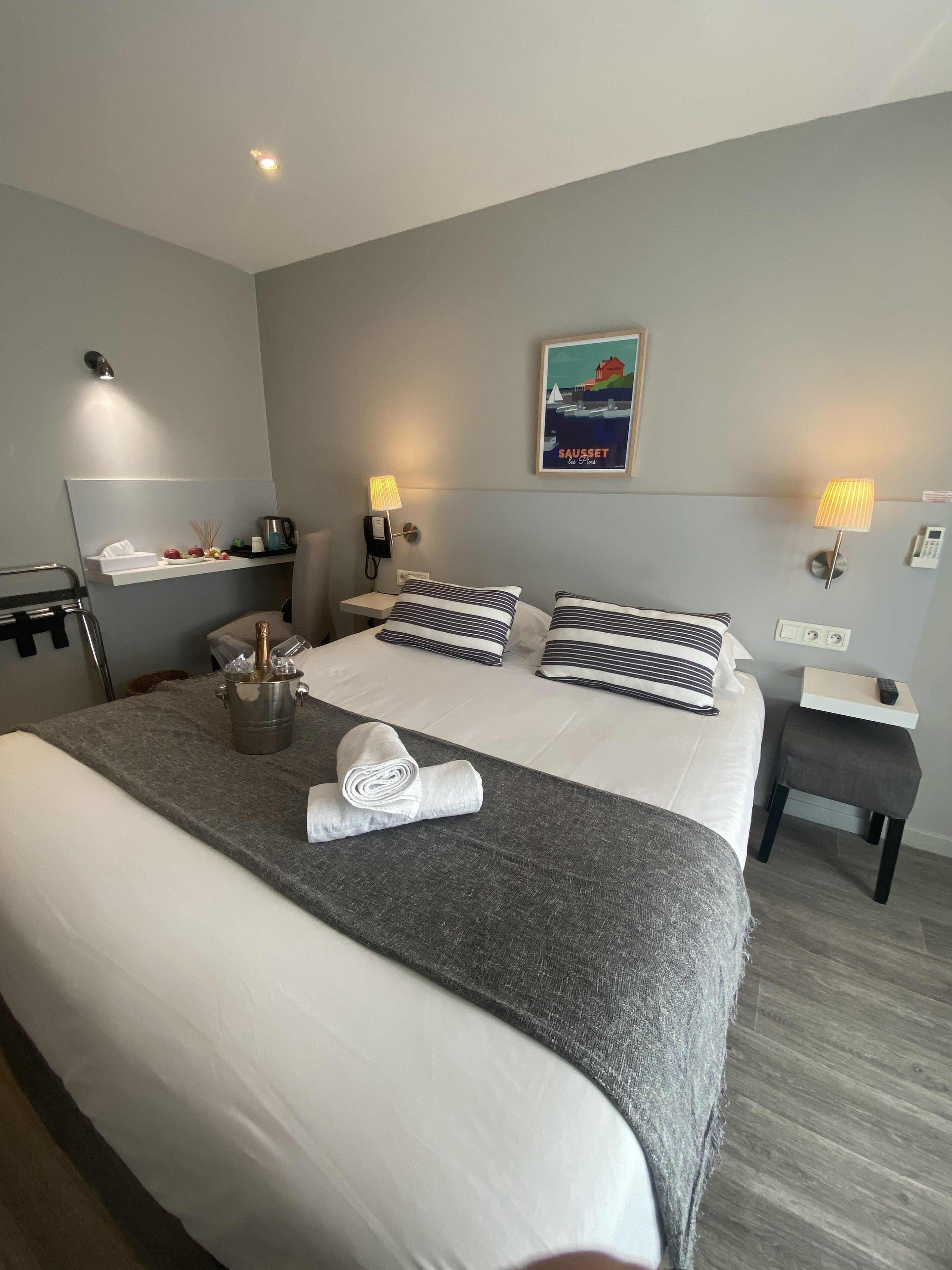 A hotel room with a large bed, bedside tables, a small desk, and a wall-mounted TV.