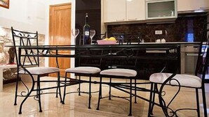 Une cuisine dotée d’un îlot central, de chaises en métal noir et d’armoires blanches.