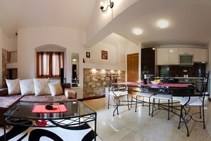 Una sala moderna con una mesa de centro de vidrio, un sofá con cojines estampados y un comedor con una mesa de vidrio y sillas de metal.