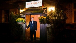 A man in a suit standing at the entrance of a hotel named 'SHERBORNE'. - Sherborne ApartHotel (Kyiv)