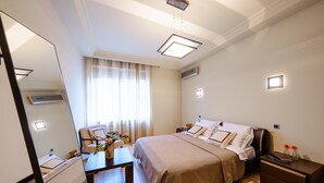 A hotel room with a bed, bedside tables, a desk, a chair, a mirror, and a window with curtains. - Sherborne ApartHotel (Kyiv)